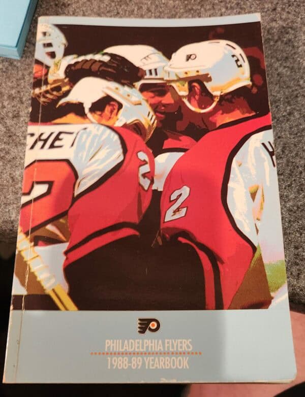 The product is a 1988-89 Philadelphia Flyers yearbook paperback with 8 autographs, including those of Bob Clarke & More